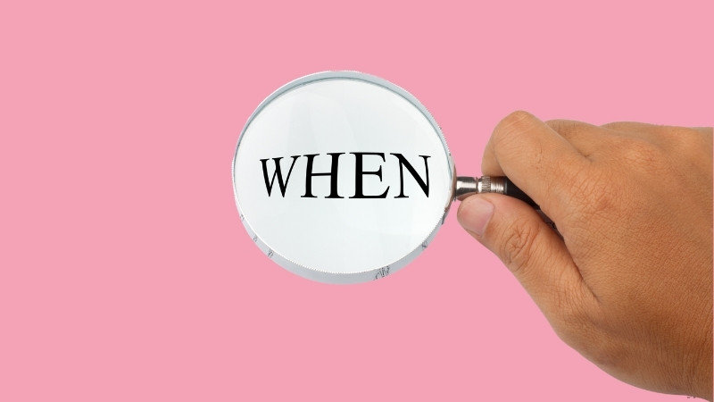 『WHEN』の英語文字に虫眼鏡をかざして見つめる構図。婚活はいつ始めるべきかを考えるイメージ